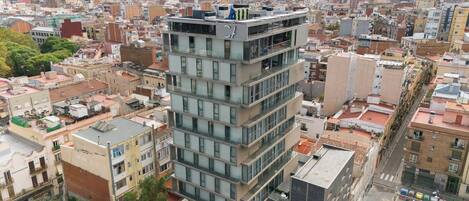 Un edificio moderno con varios pisos y balcones, rodeado de otros edificios.