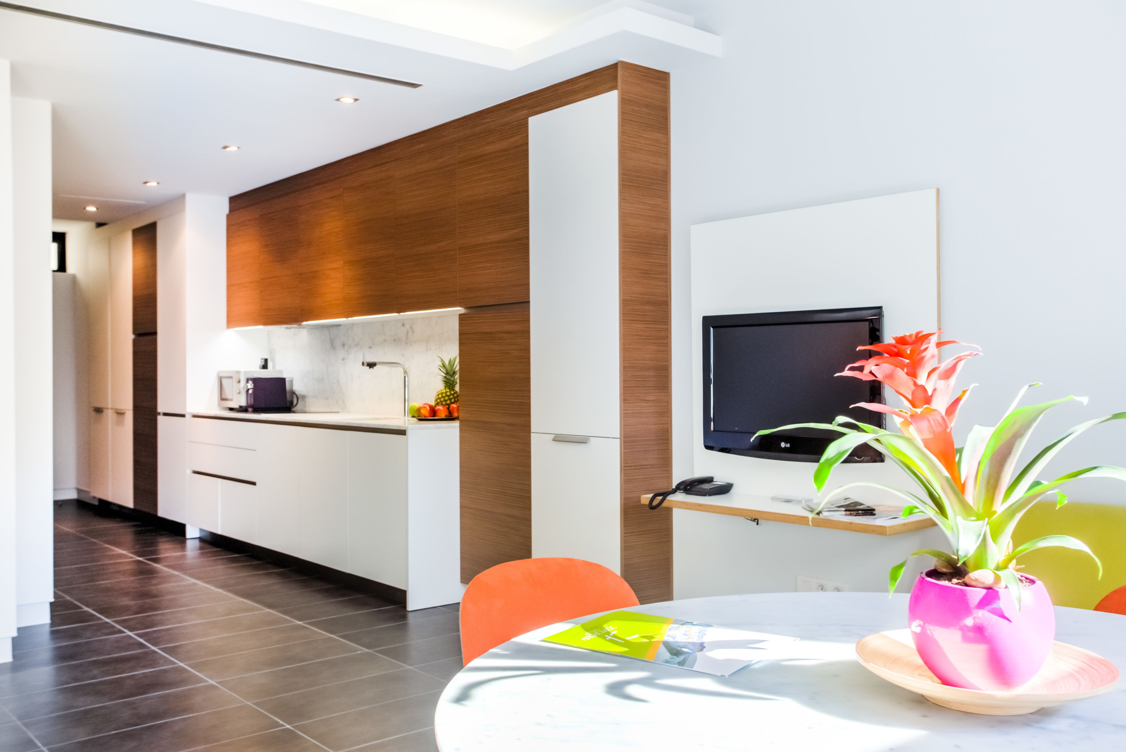 Eine moderne Küche mit weißen Schränken, einer Holz-Akzentwand, einem eingebauten Backofen und einer kleinen Kochinsel mit Mikrowelle.