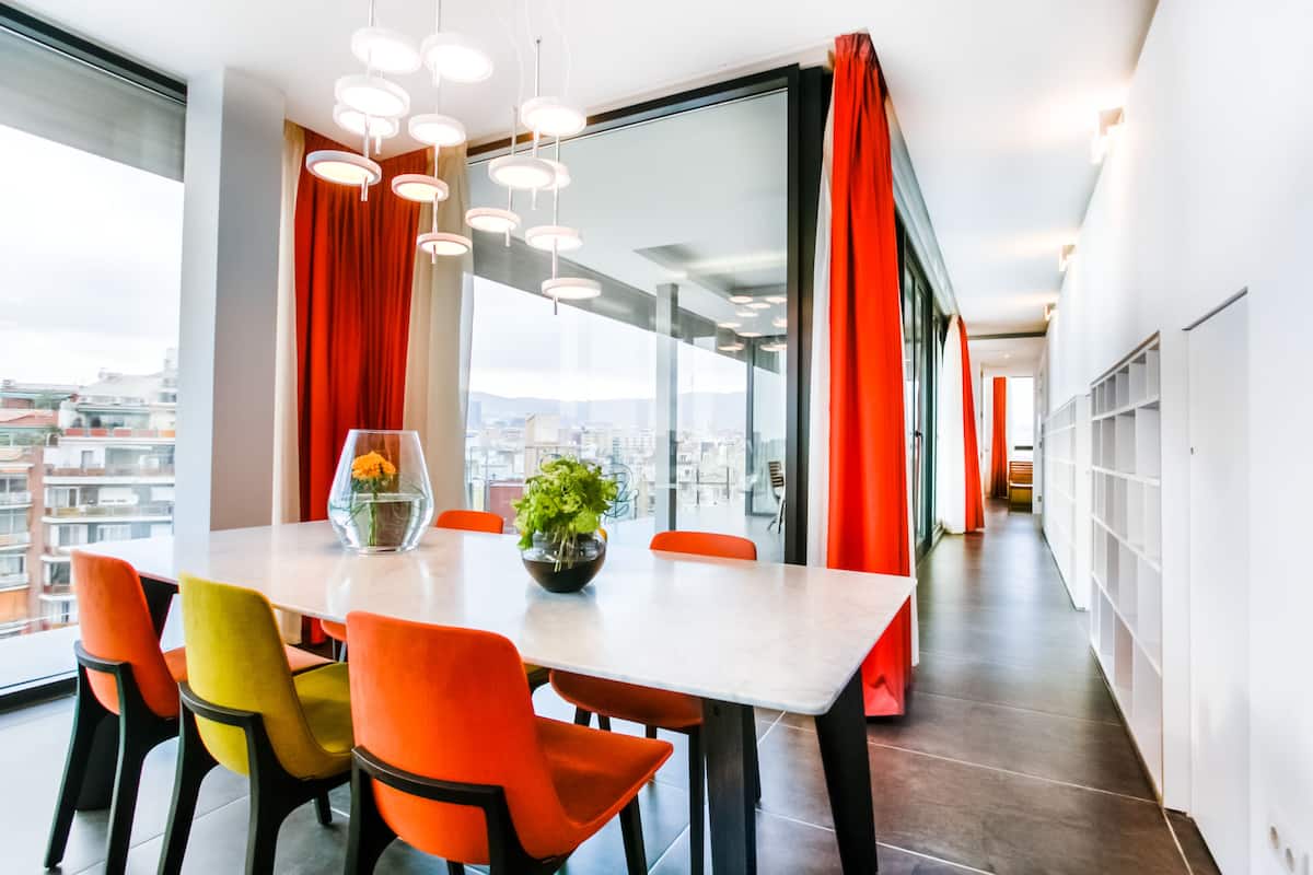 A modern dining area with a table, chairs, and a view through large windows.