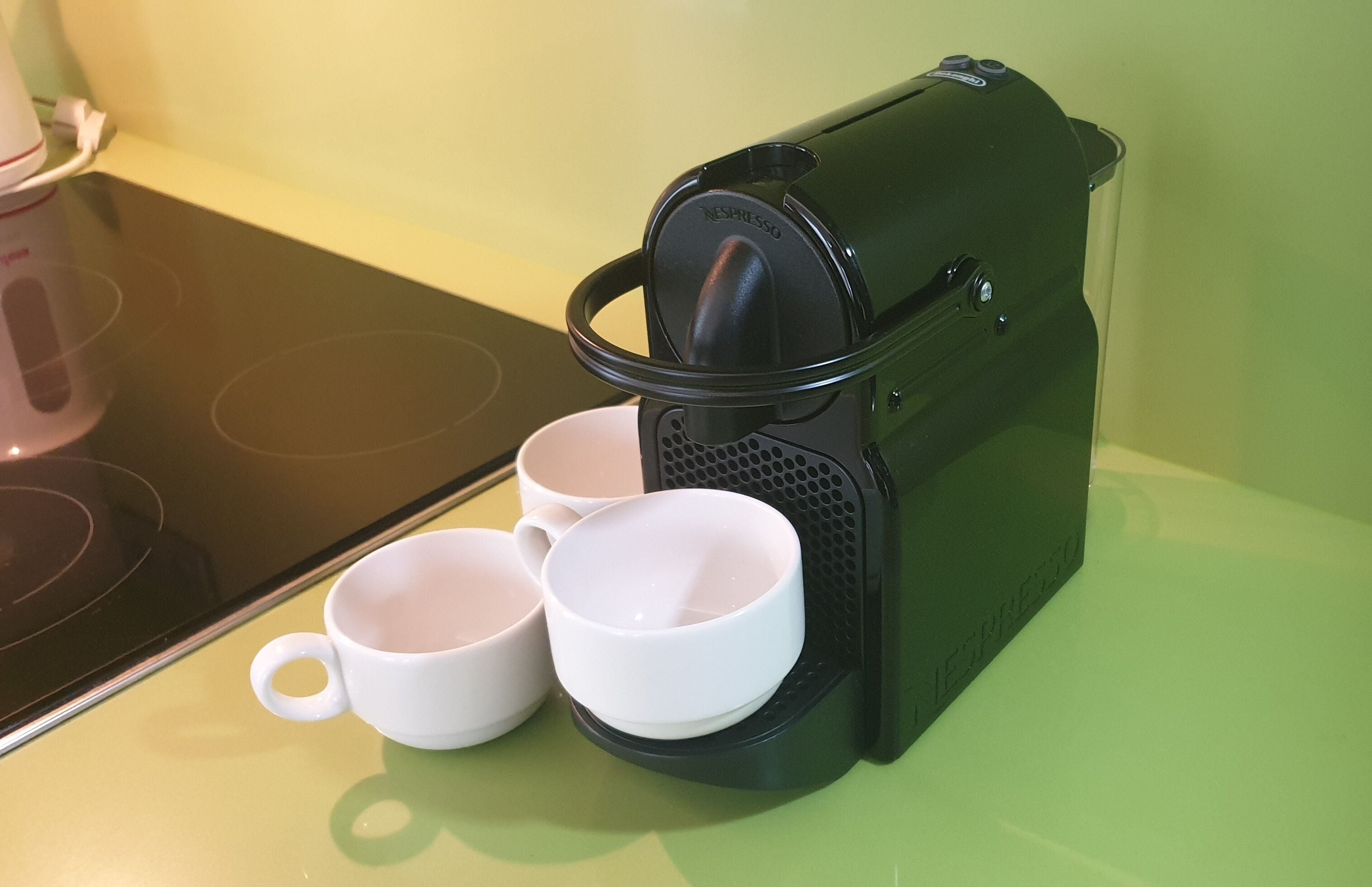 A Nespresso coffee machine with two white cups placed on its drip tray.