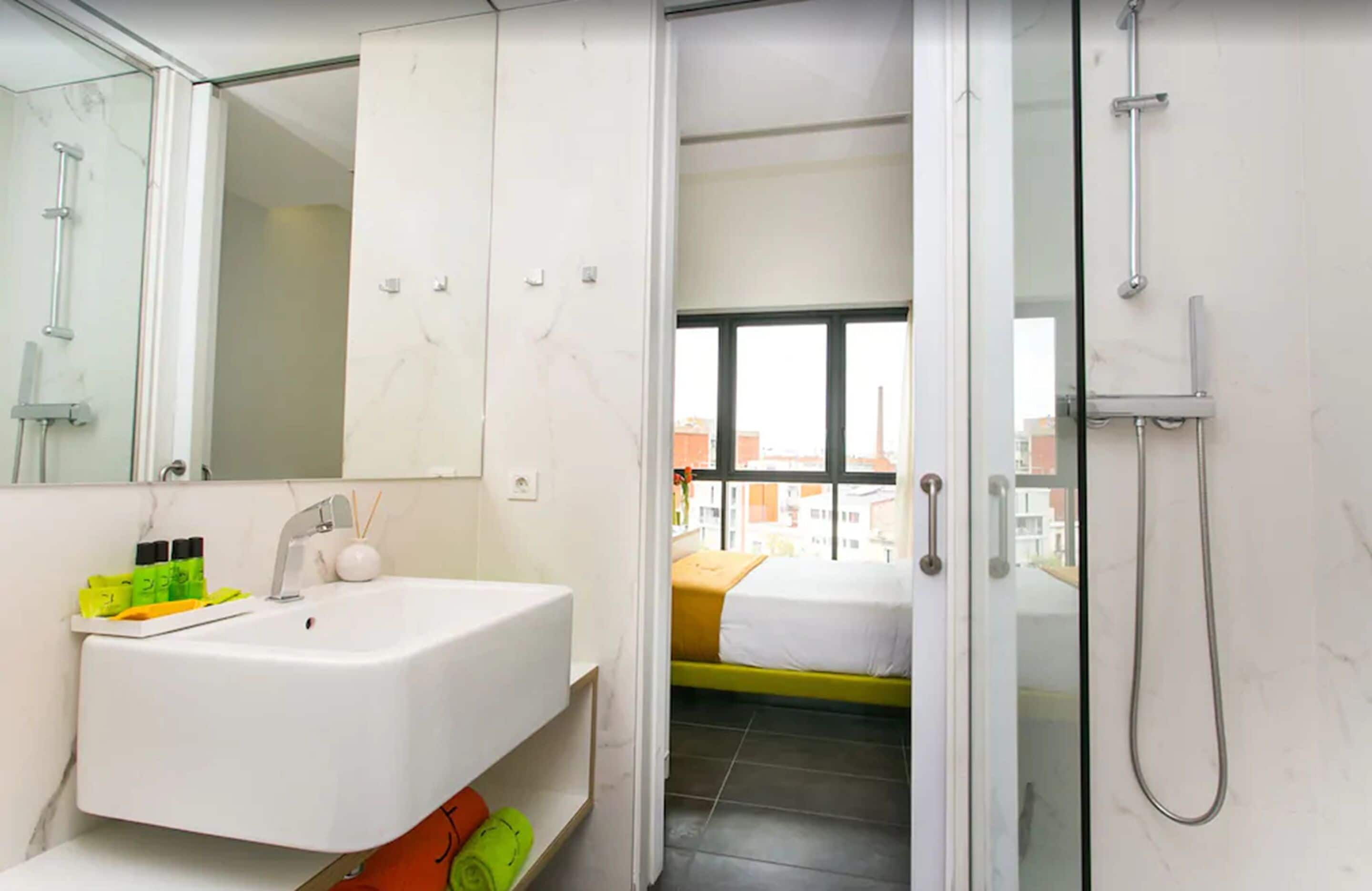A modern bathroom with a white sink, mirror, and shower.