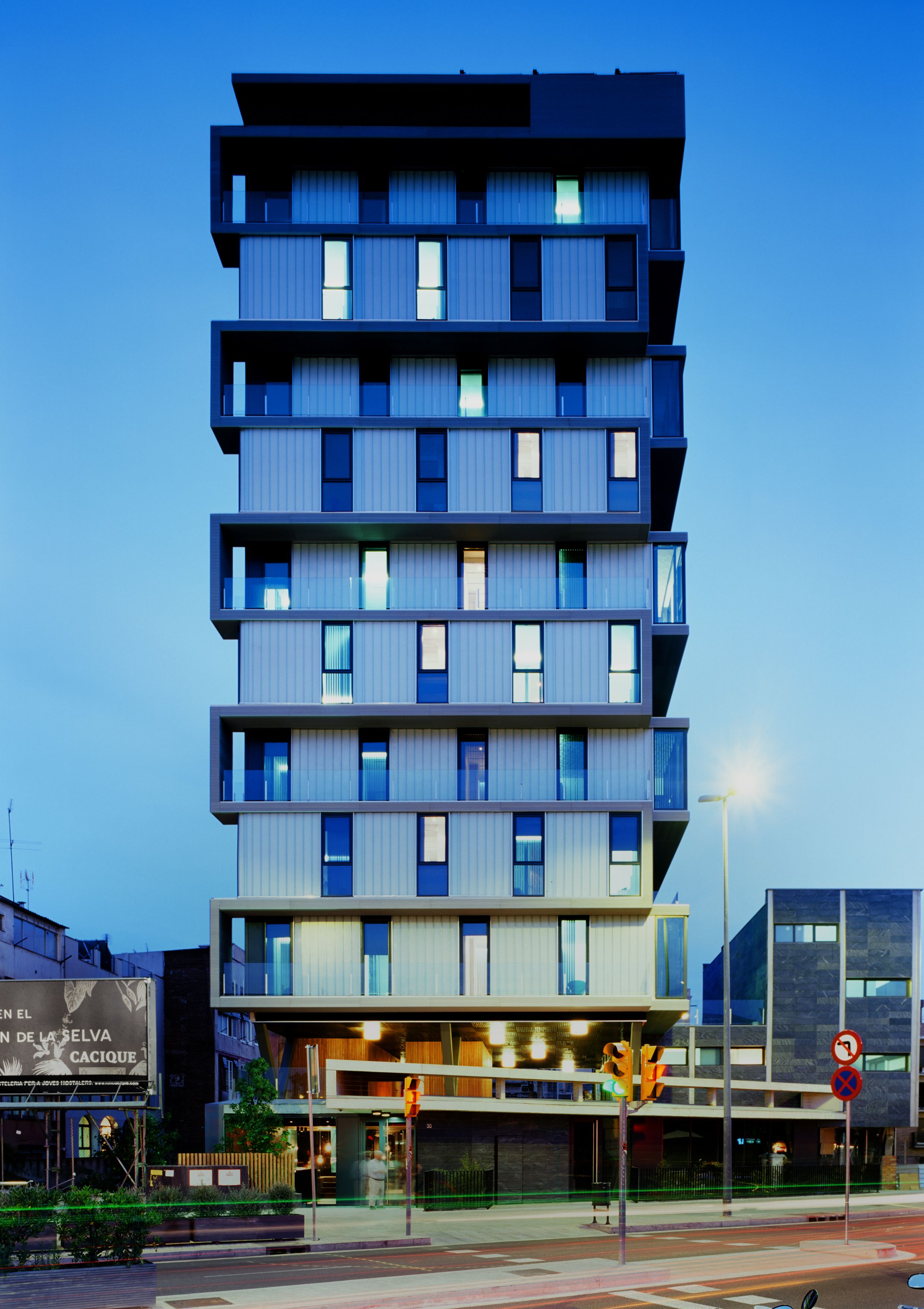 Un edificio de varios pisos con un diseño moderno, con balcones en cada planta.