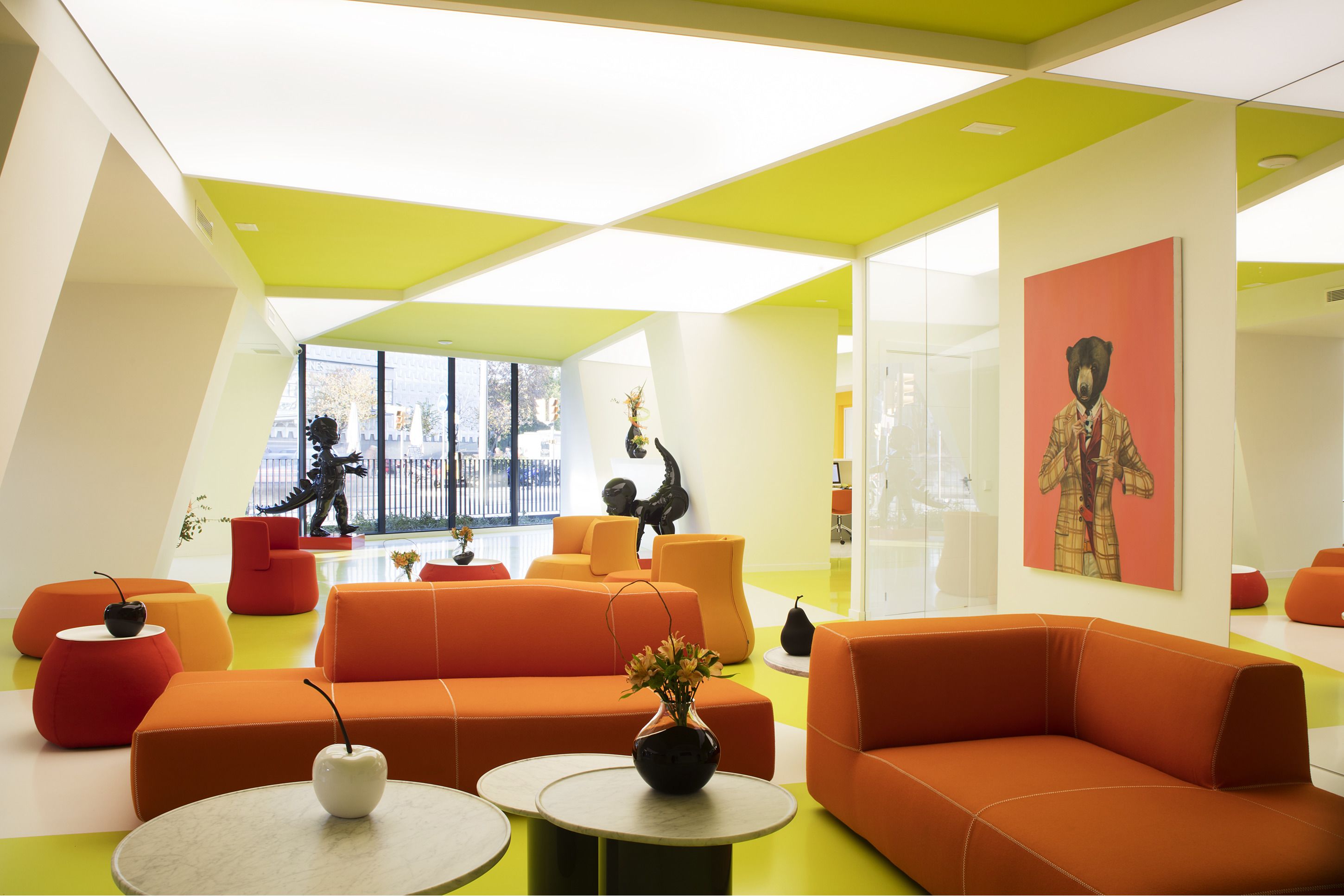 A modern interior with orange sofas, a vase with flowers, and a bear painting on the wall.
