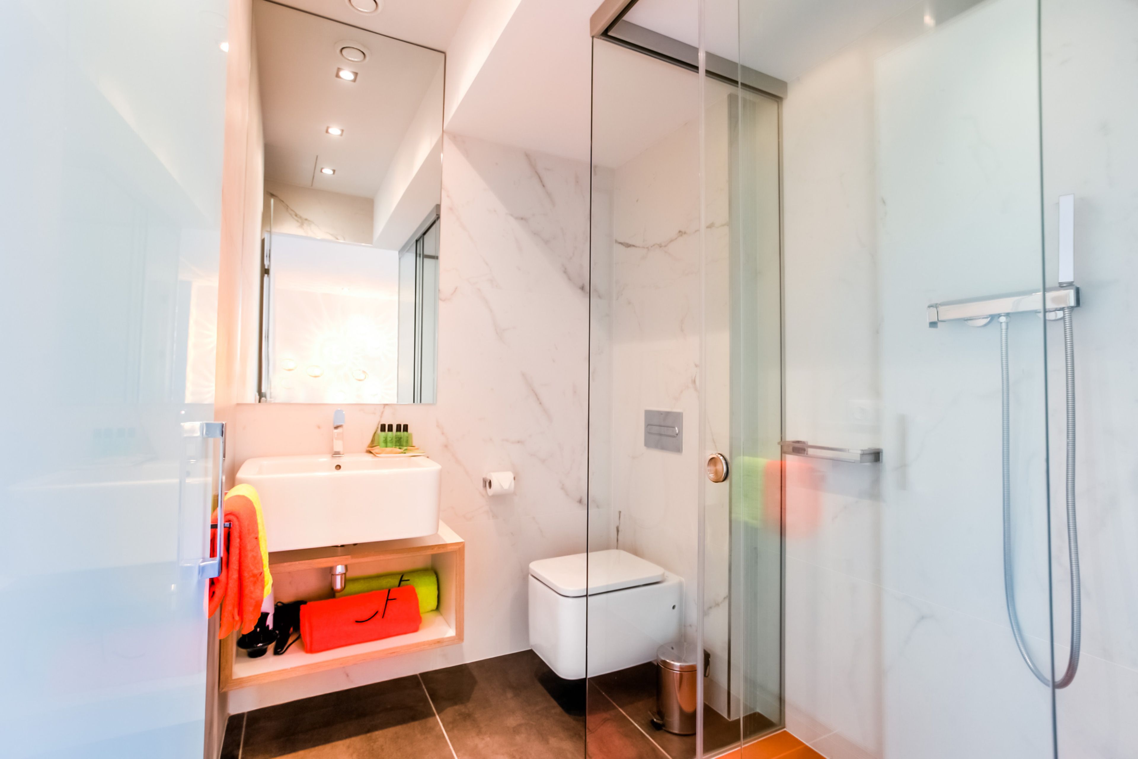 Une salle de bain moderne avec une douche à parois de verre, un lavabo blanc et des toilettes.