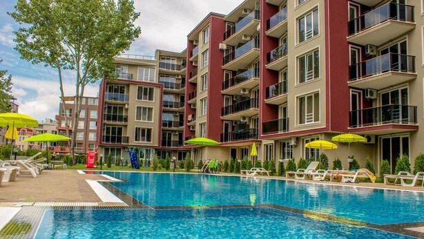 A swimming pool with lounge chairs and umbrellas, surrounded by multi-story buildings with balconies. - Menada VIP Park Apartments (Sunny Beach)
