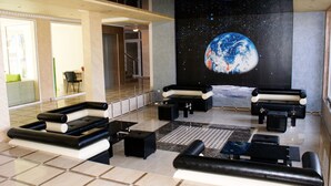 A lobby with a large mural of Earth and space, black and white sofas, and a tiled floor. - Menada VIP Park Apartments (Sunny Beach)