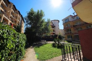 Surrounded by lush greenery, this residential building offers a serene atmosphere with multiple balconies and windows.
