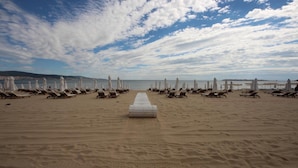 A beach with rows of sun loungers and umbrellas, a central pathway, and a clear sky. - Menada Diamant Residence Apartments (Sunny Beach)