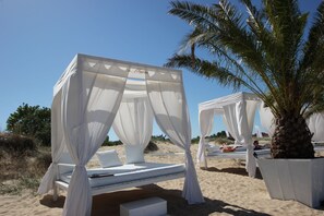 Un resort frente a la playa con camas con dosel blanco y palmeras.
