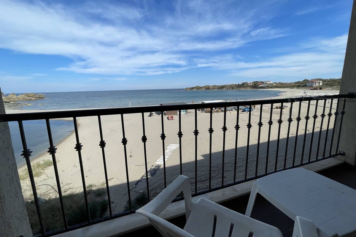 Een balkon met uitzicht op een zandstrand en de zee.