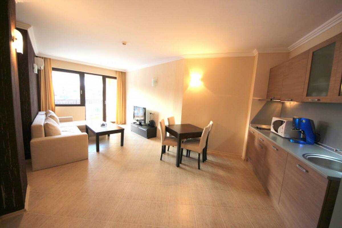 Een compacte hotelkamer met een zithoek, een eettafel, een bank, een televisie, een magnetron en een kitchenette.
