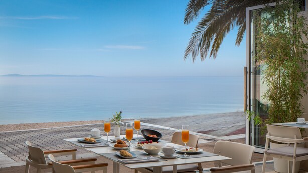 Una tavola per la colazione con vista sul mare, che include una spiaggia e montagne all'orizzonte.