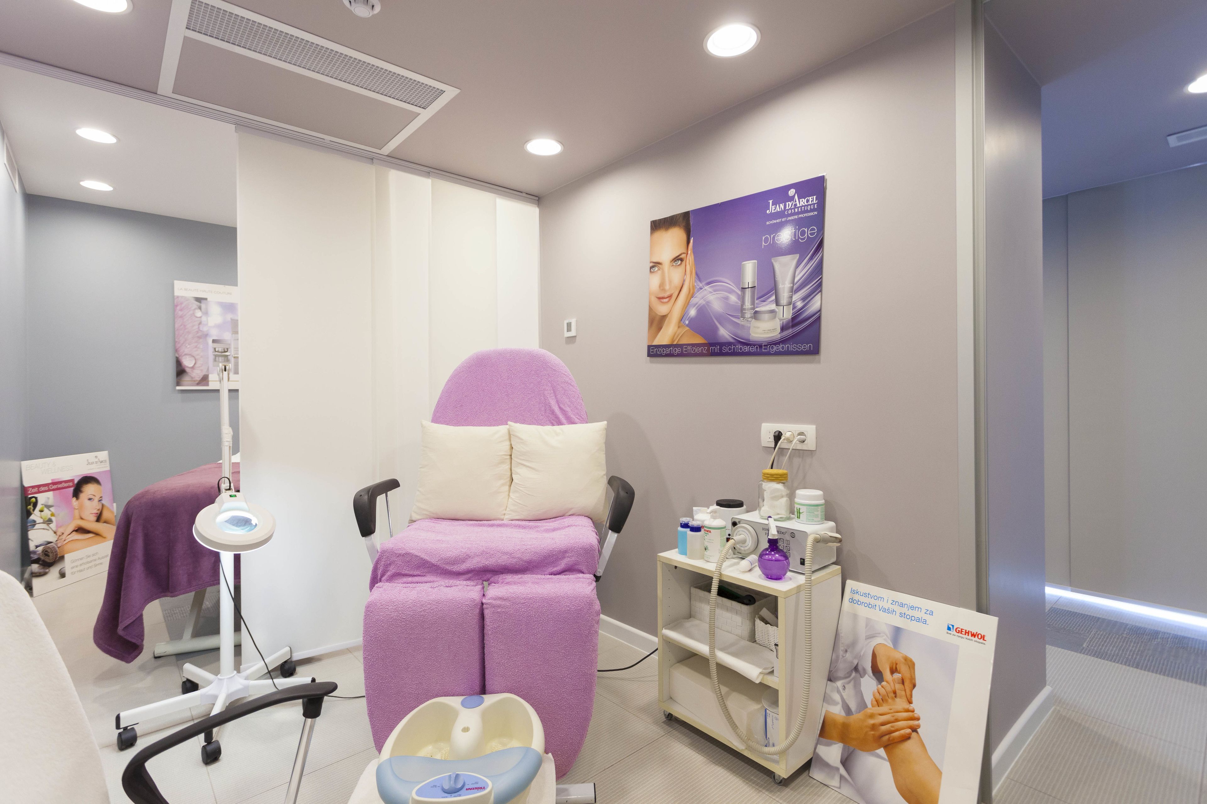 Une salle de spa moderne équipée d’un fauteuil de massage, d’un bain de pieds et d’une étagère contenant des produits de soins pour la peau.