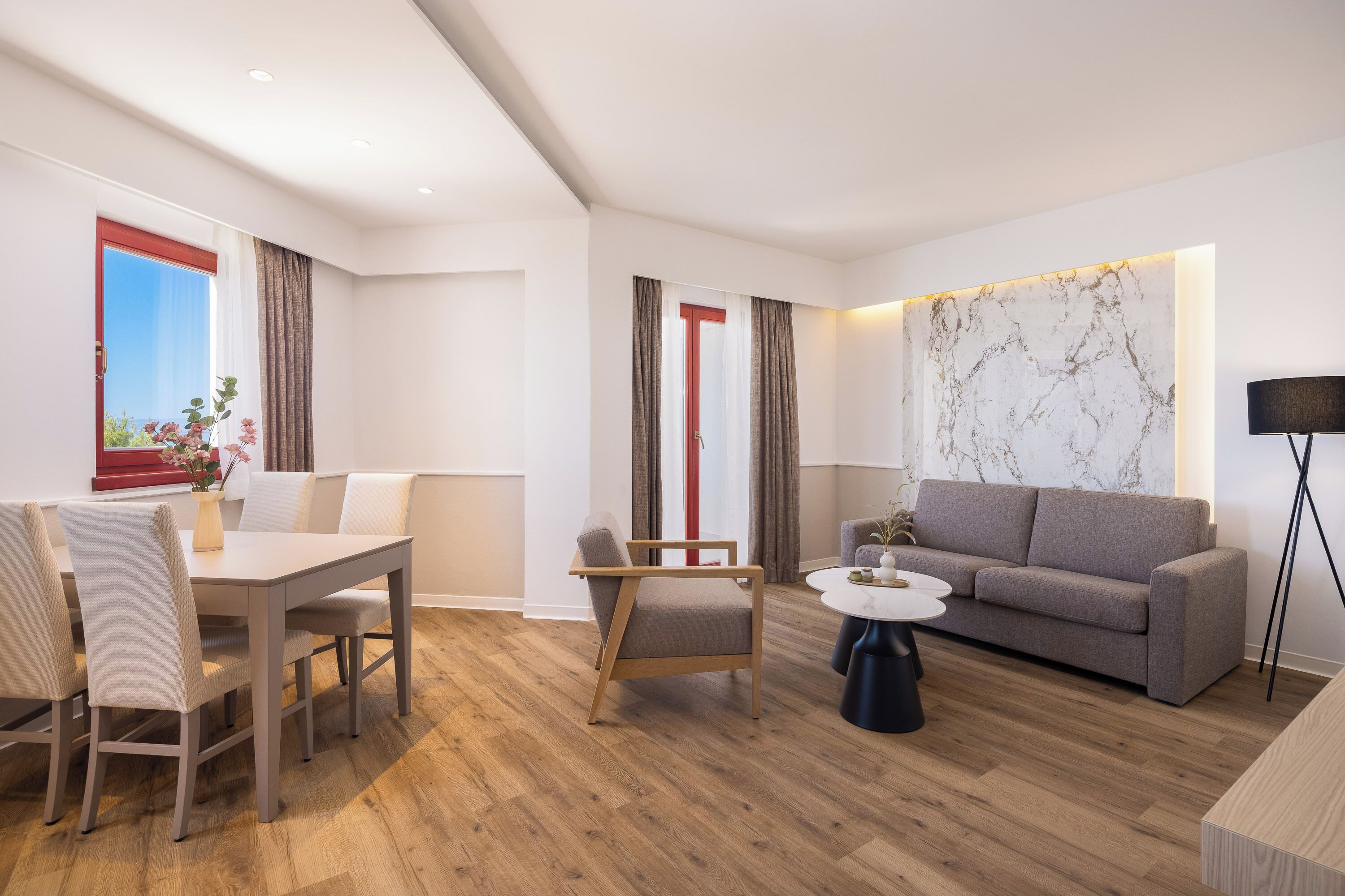 A modern living room with a dining area, a sofa, a coffee table, and a marble accent wall.
