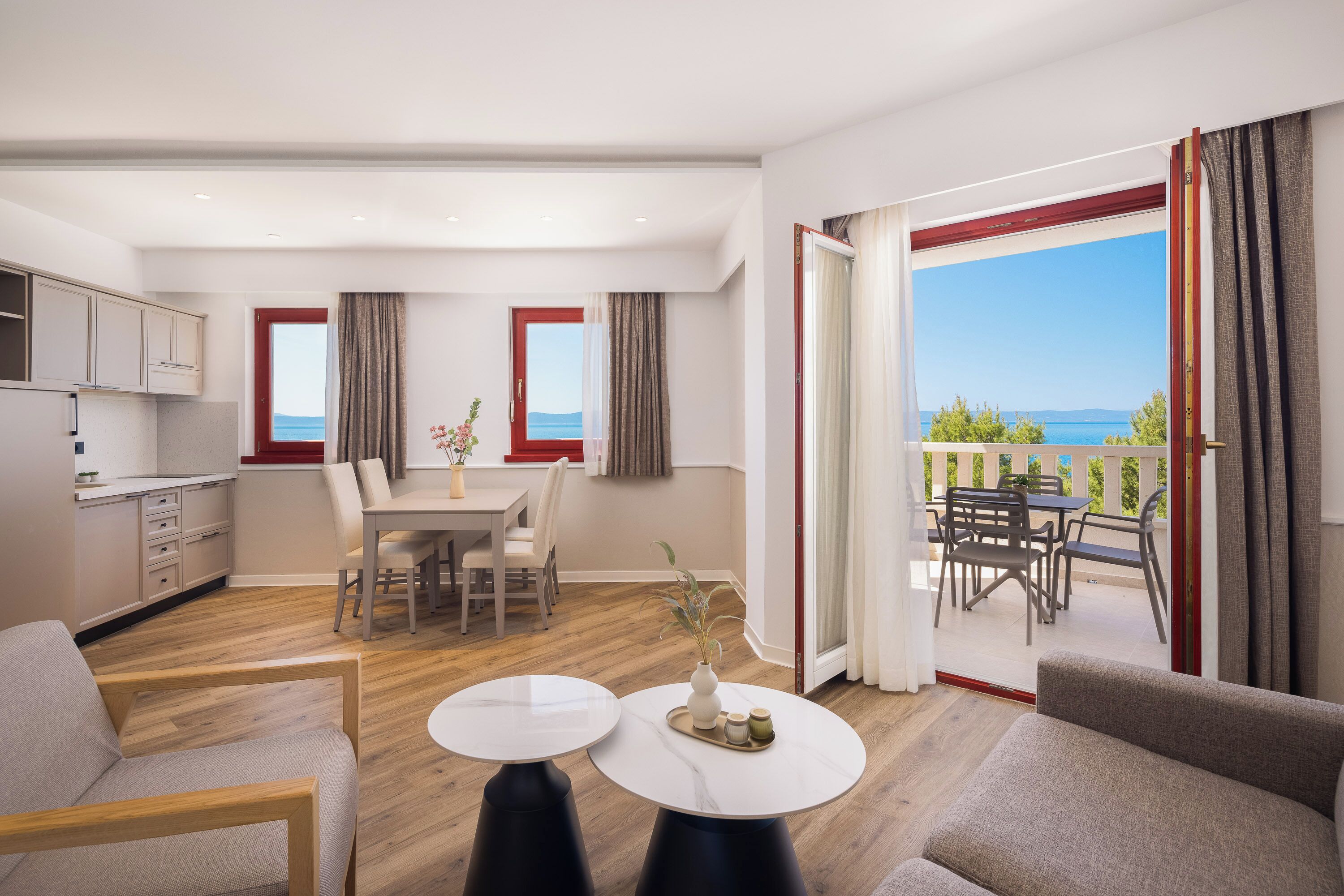 A modern living room with a dining area, kitchen, and a balcony with a view.