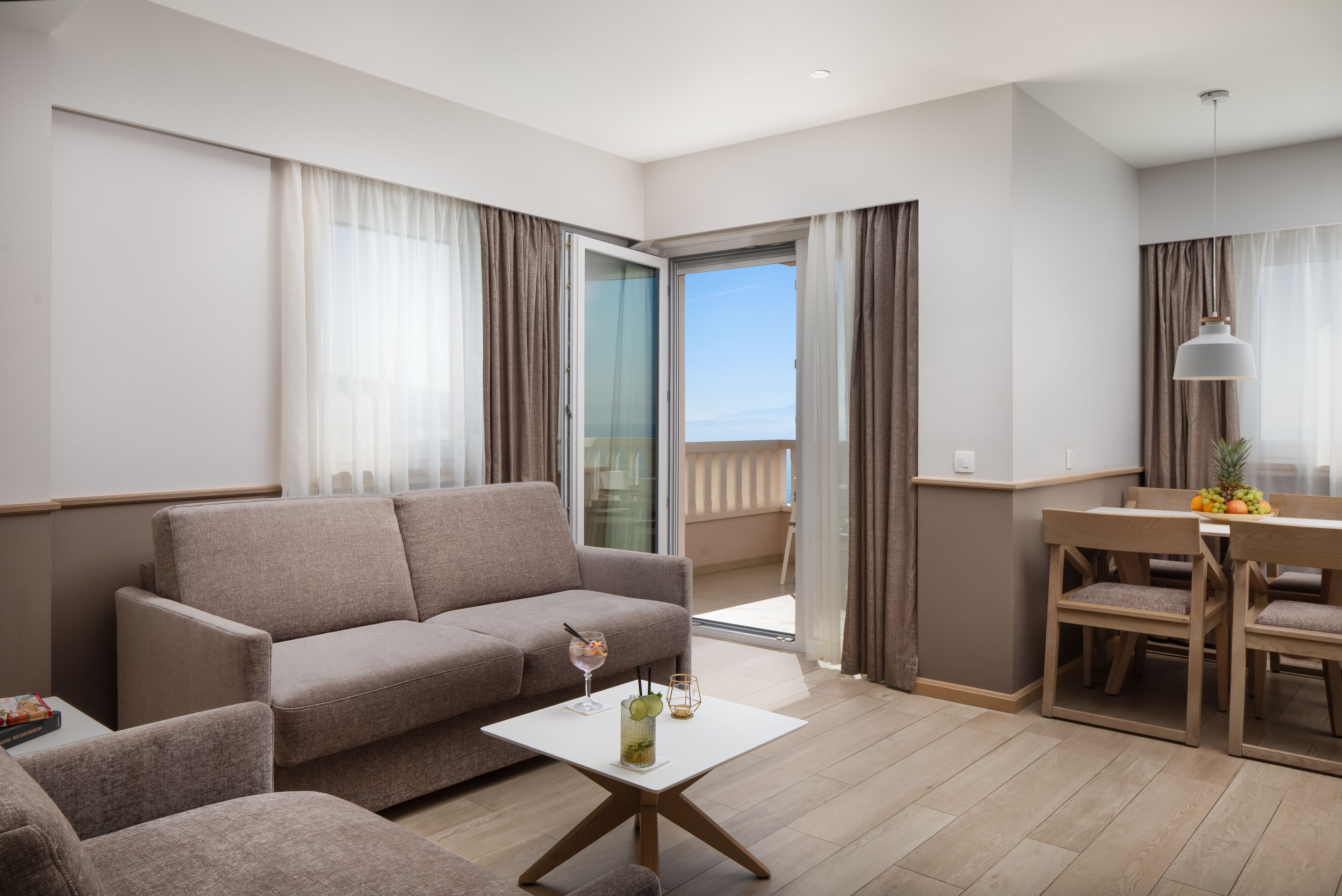 Una sala de estar moderna con un sofá, una mesa de centro con una bebida, y un comedor con sillas y una mesa.