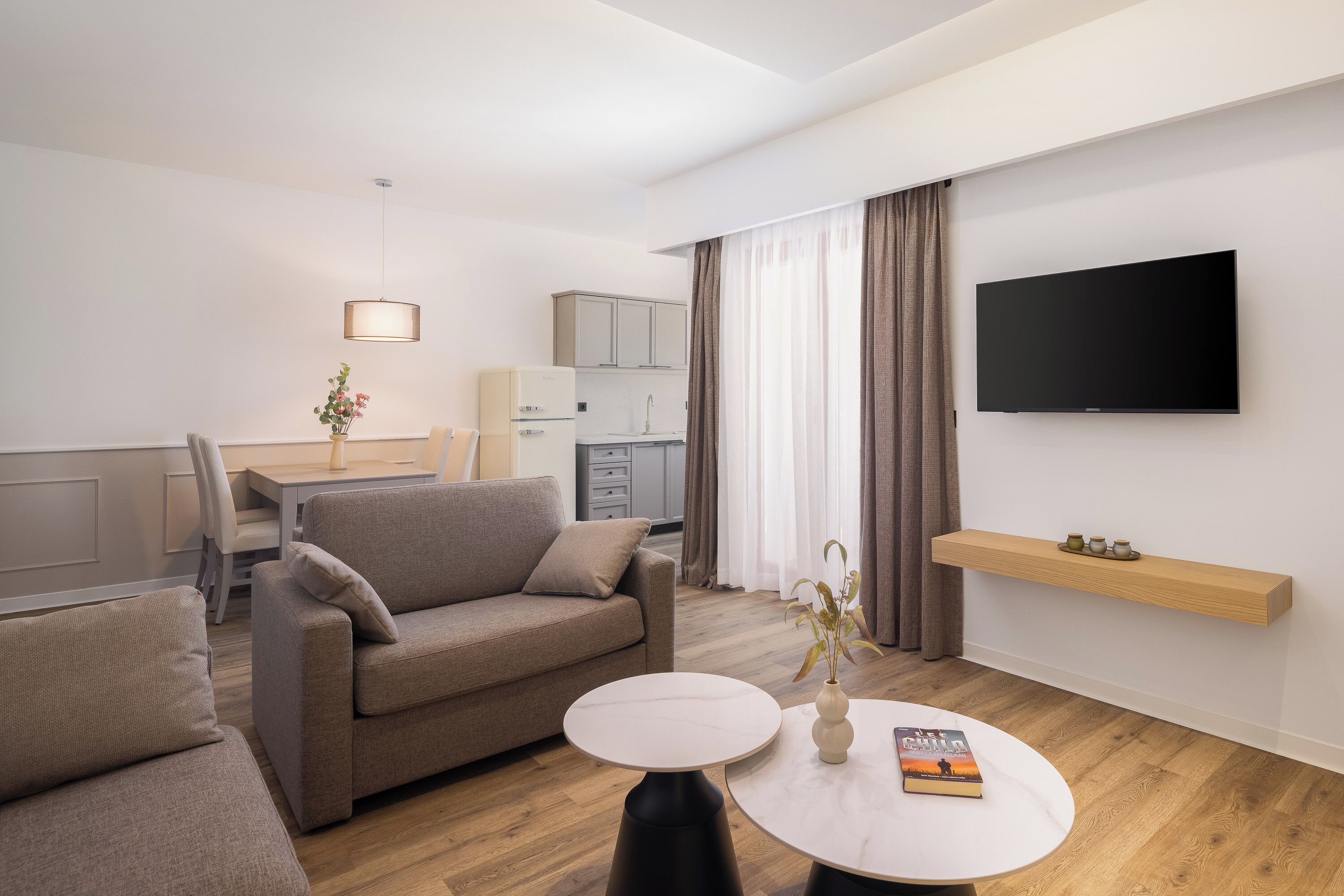 A modern living room with a sofa, a round coffee table, and a flat-screen TV mounted on the wall.
