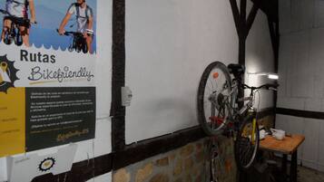 A room with a bicycle leaning against a wall, a poster advertising bike routes, and a stone wall.