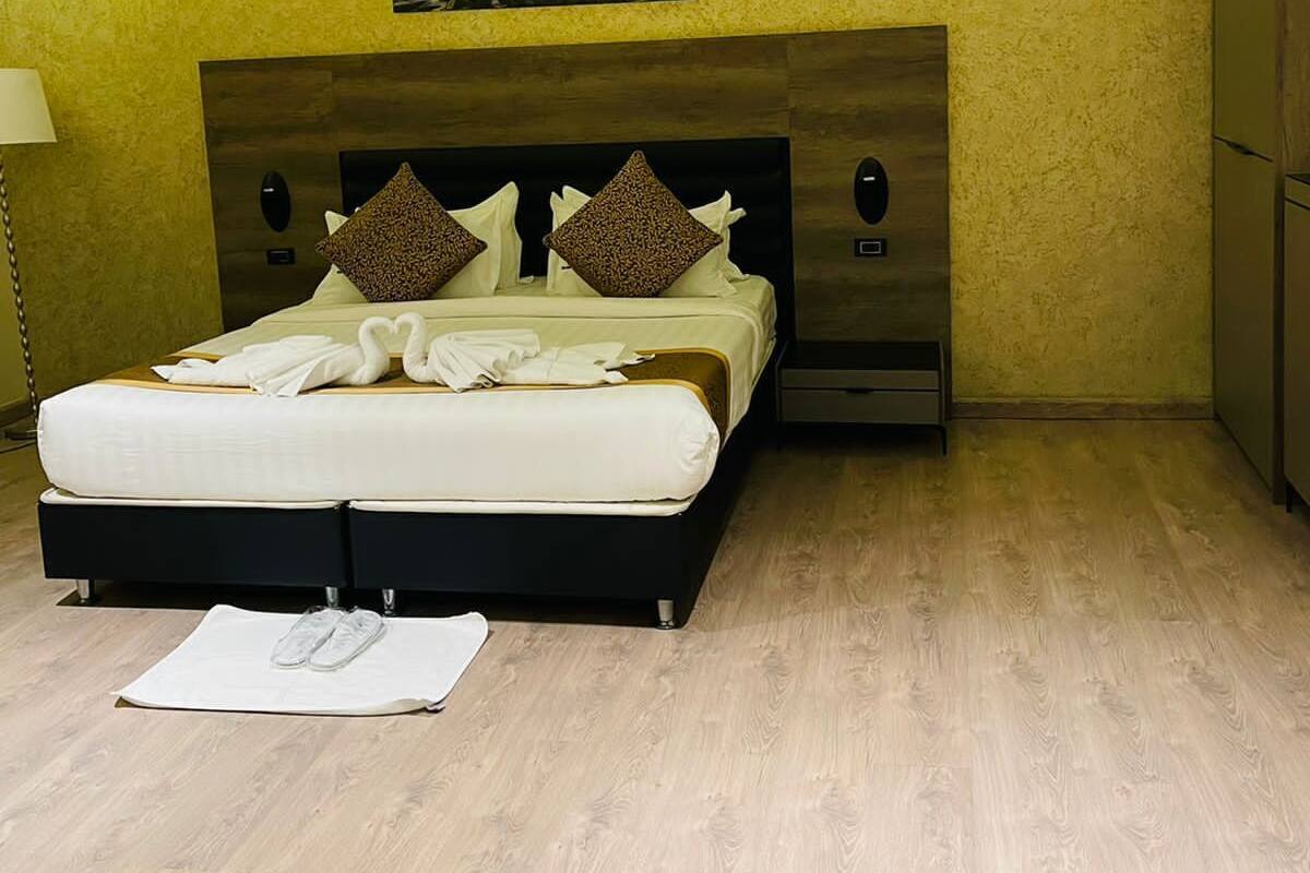 A modern bedroom with a bed, wooden headboard, and a picture above the bed.