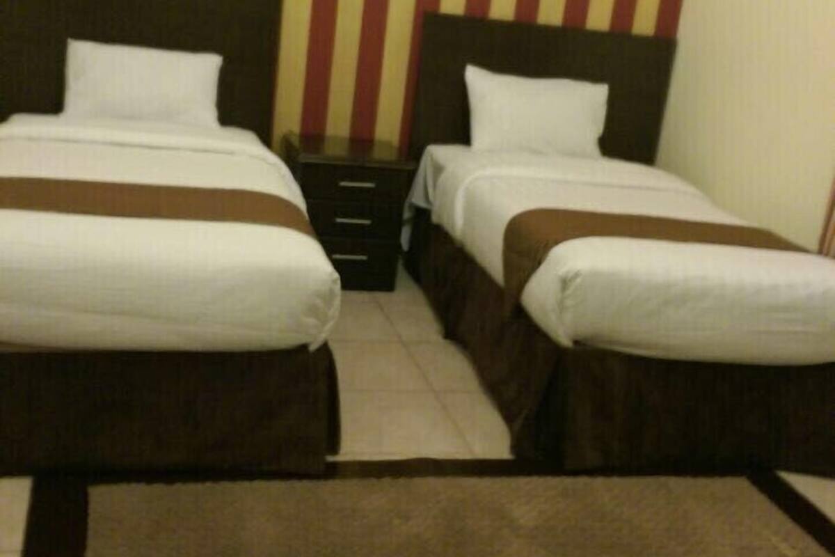 A hotel room with two beds, a framed picture on the wall, and a brown carpet.