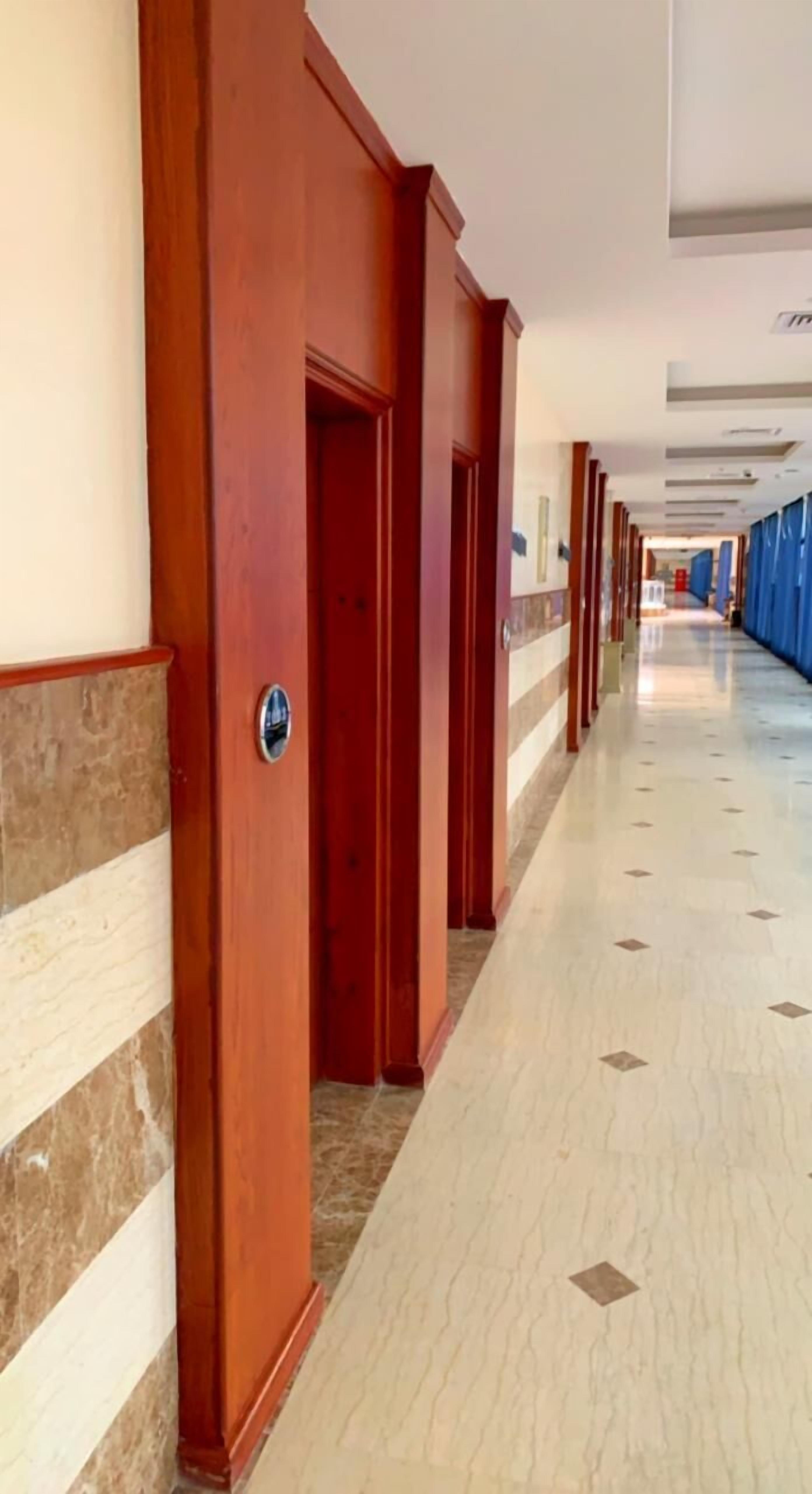 A hotel corridor with wooden doors and a tiled floor.