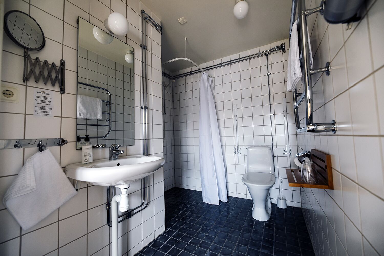 A bathroom with a white sink, a toilet, a shower with a white curtain, and a mirror.