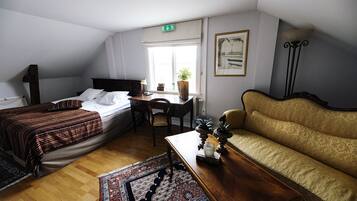 Una habitación con cama, escritorio, sofá y ventana con planta.