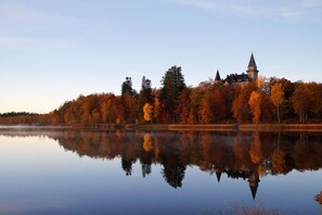 A serene lakeside view with a historic building surrounded by autumn foliage. - Teleborgs Slott (Växjö)
