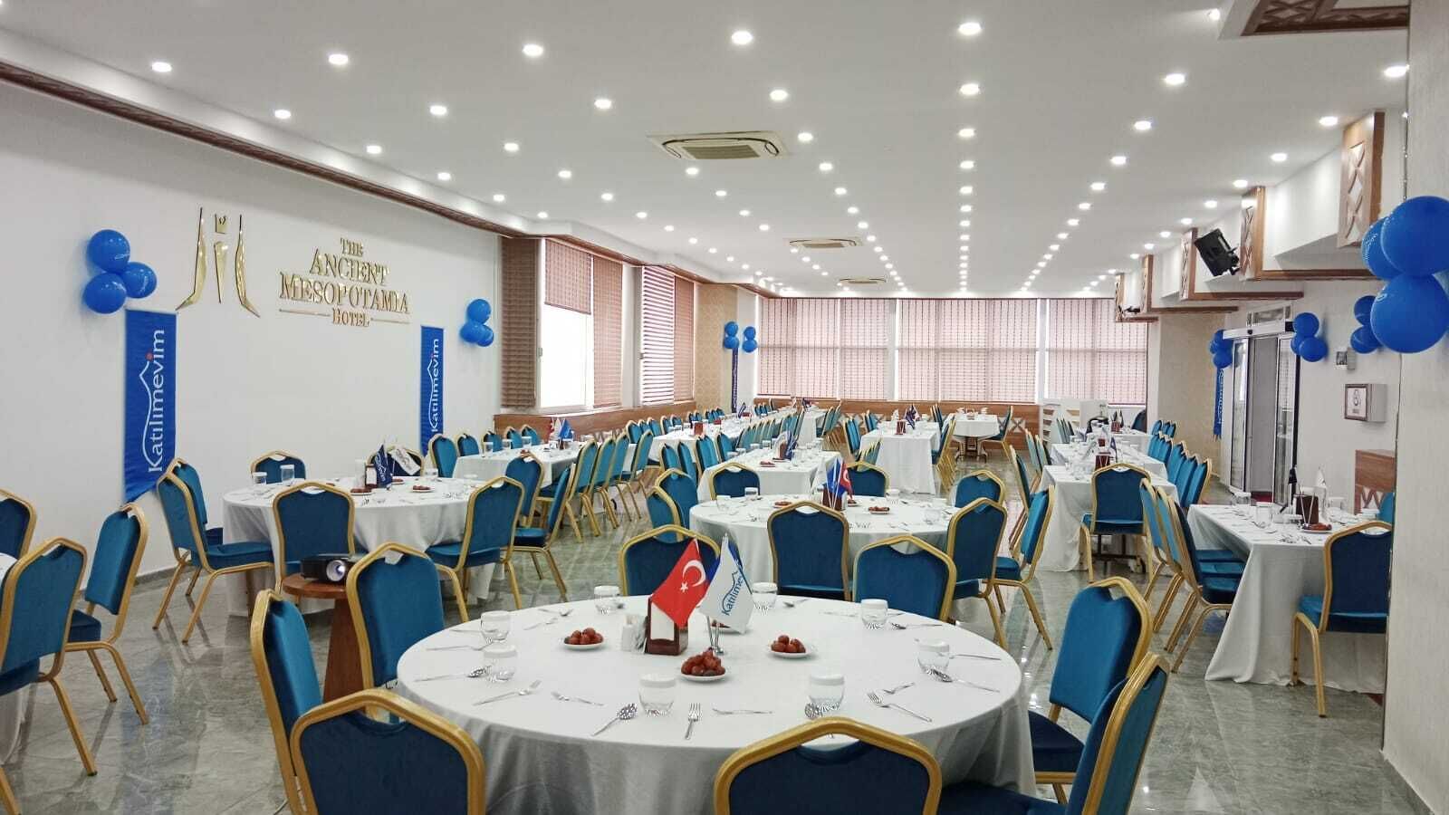 A conference room with round tables, blue chairs, and white tablecloths.