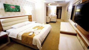 A hotel room with a bed, a TV, a desk, and a chair. - The Ancient Mesopotamia Hotel (Batman)