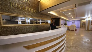 A reception area with a marble wall and a receptionist. - The Ancient Mesopotamia Hotel (Batman)