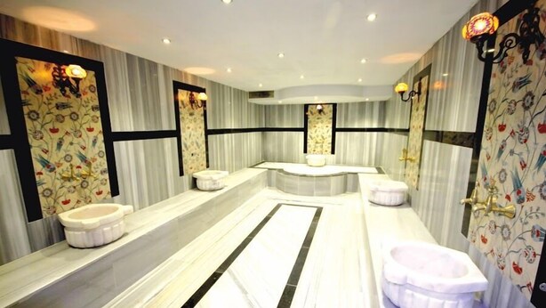 A modern bathroom with a large mirror, a bathtub, and a toilet. - The Ancient Mesopotamia Hotel (Batman)