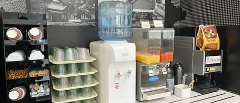 A beverage station with a water dispenser, coffee machine, and a juice dispenser.