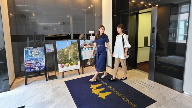 A modern lobby with a glass wall, a reception desk, and a blue carpet with a logo. - Sanco Inn Yokkaichi Ekimae (Yokkaichi)