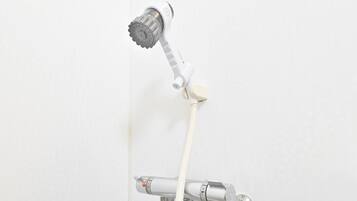 A showerhead with a white handle and a flexible hose attached to a wall-mounted faucet.