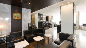 A modern hotel lobby with seating areas, a reception desk, and a large mirror. - Sanco Inn Yokkaichi Ekimae (Yokkaichi)