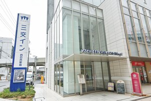 A modern building with large glass windows, a signboard with Japanese text, and a visible entrance.