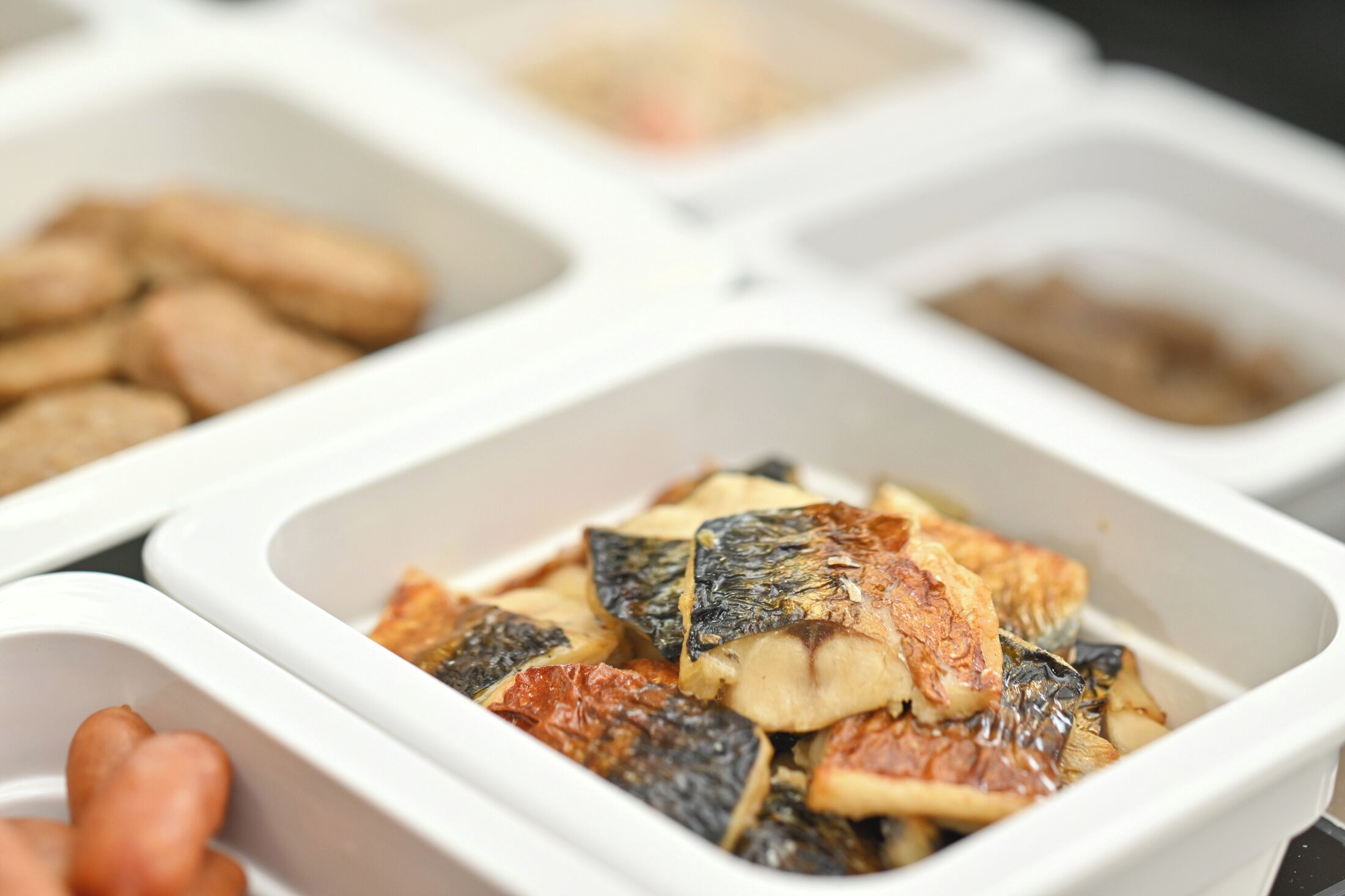 A food display with various dishes in white containers.
