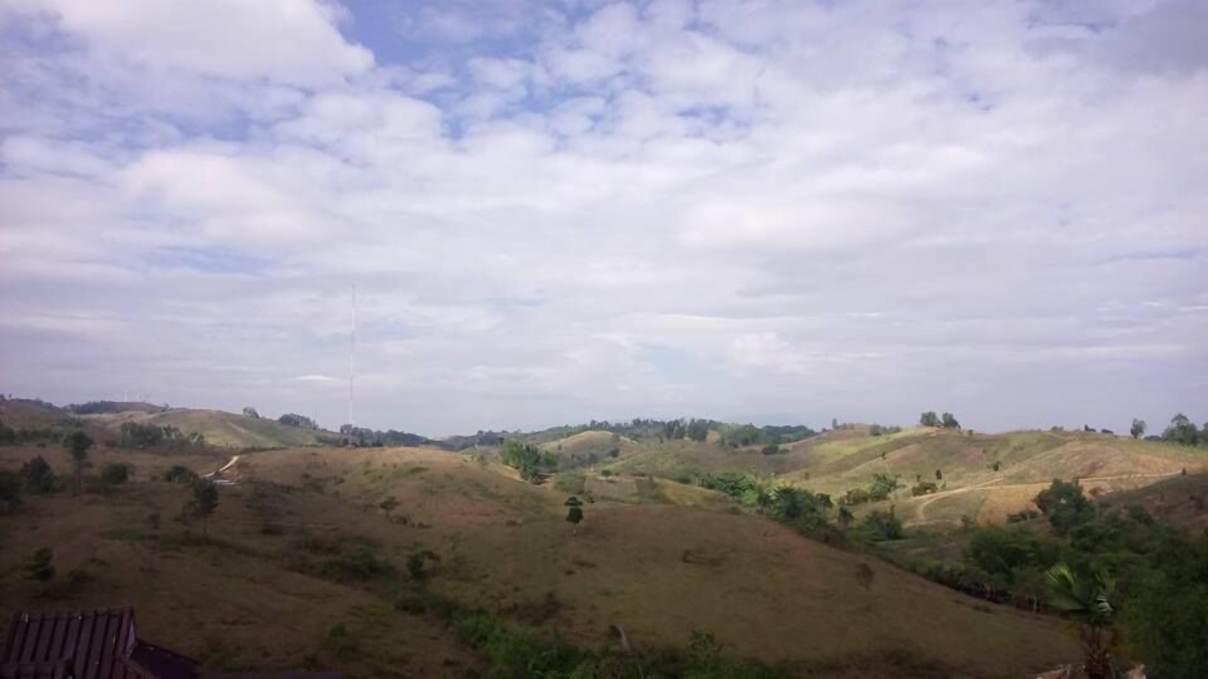 A rural landscape with rolling hills and sparse vegetation.