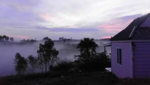 A house with a sloped roof, surrounded by trees and a foggy landscape. - Lovely Farm (Khao Kho)