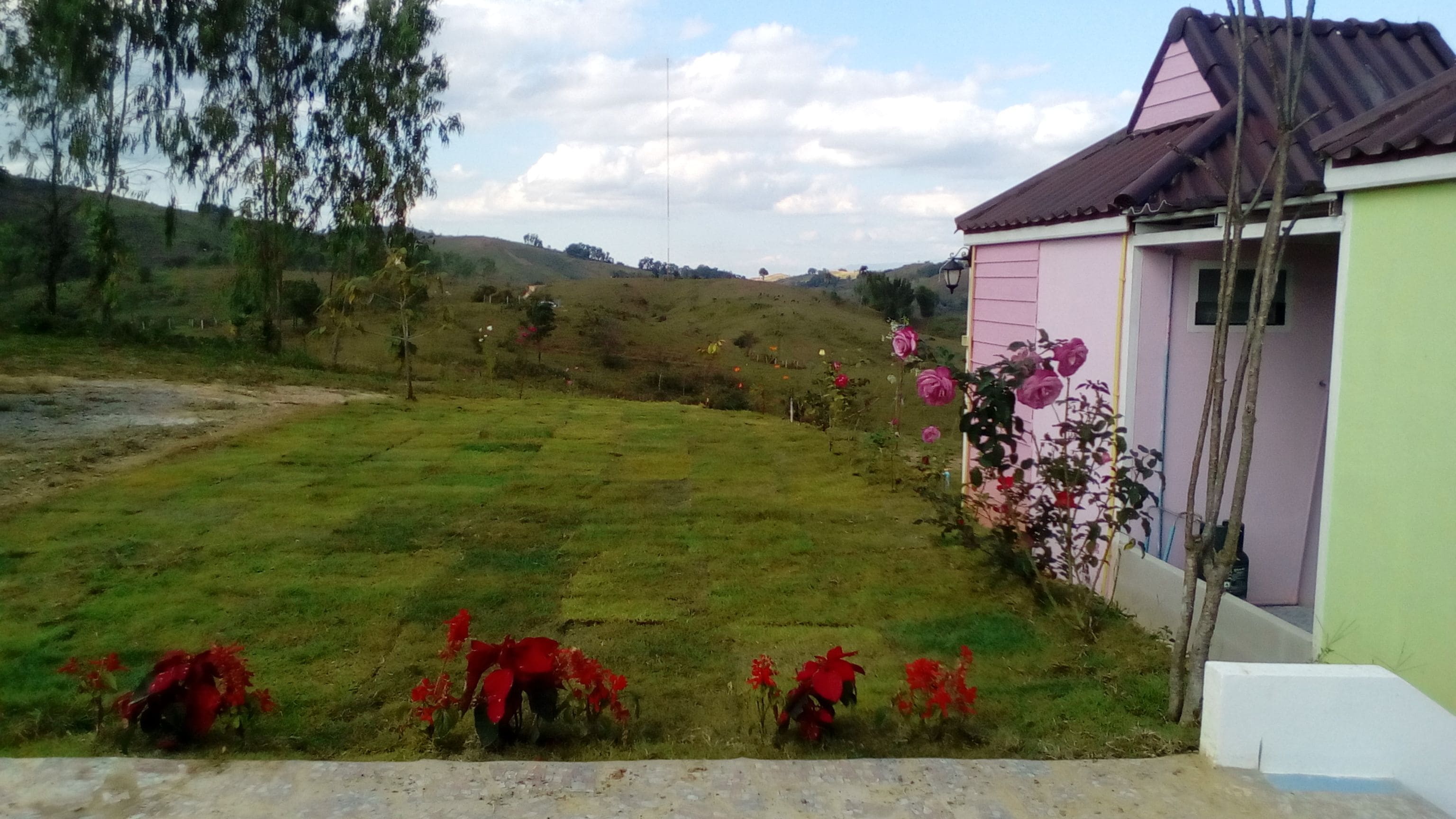 A grassy area with a pink building and a white structure.