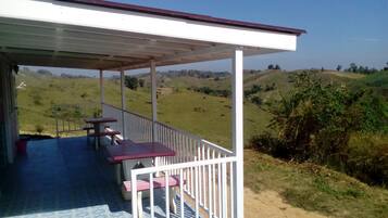 Un espacio de estar al aire libre cubierto con mesas y sillas, con vistas a un paisaje montañoso.