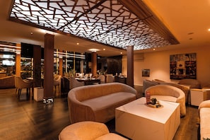 Un interior moderno con una zona de estar central, un bar y un comedor.