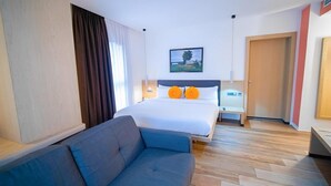 A hotel room with a bed, a sofa, a nightstand, and a painting on the wall. - SV Chrome (Abuja)