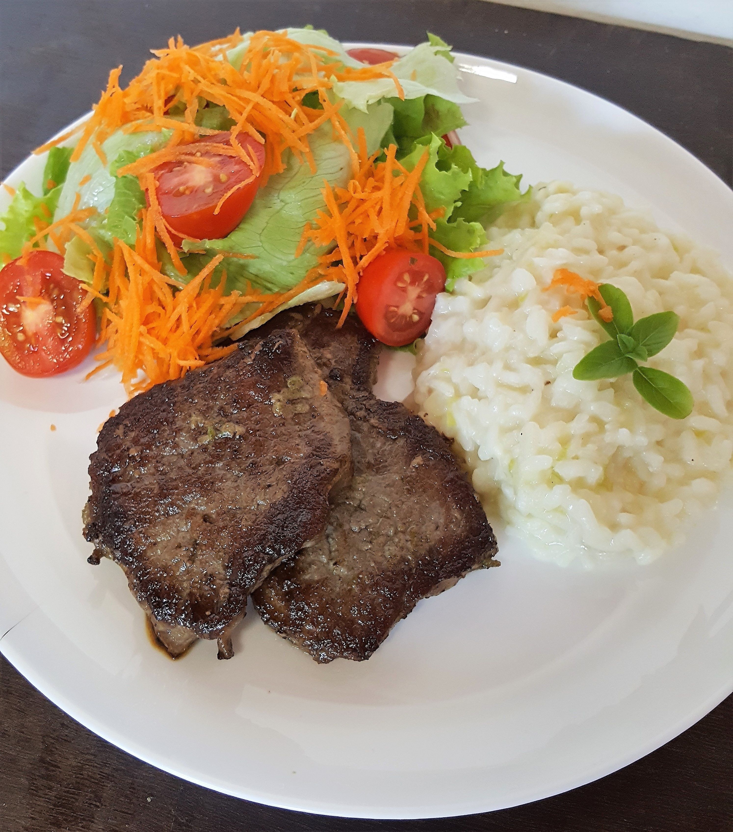 Un plato con carne a la parrilla, arroz y ensalada.