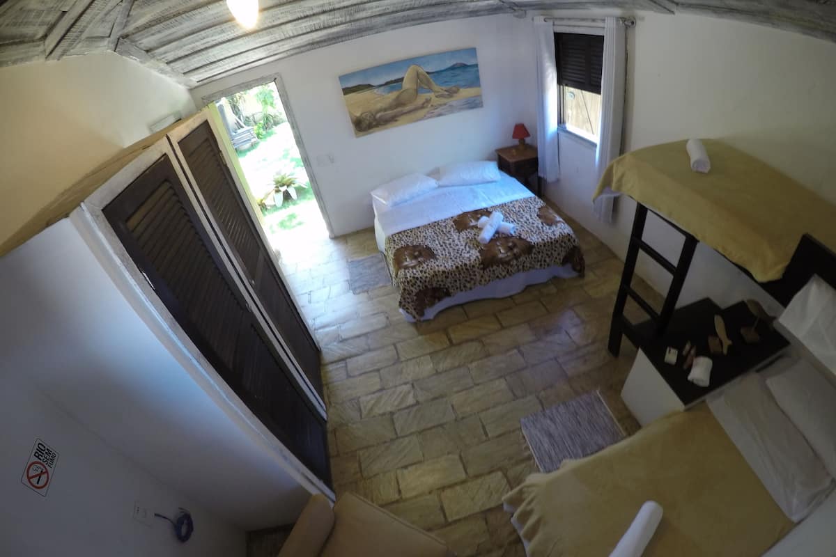 A room with a bed, a chair, a small table, and a painting on the wall.