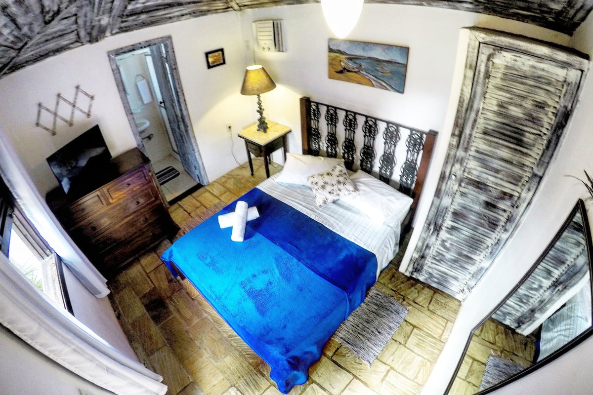 A room with a bed, a desk, a lamp, and a painting on the wall.