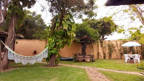 A garden with a hammock, a picnic table, and a white umbrella. - Morada do Sol Guest House (Búzios)