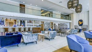 A modern hotel lobby with seating areas, a bar, and a decorative wall. - MARITIM Paradise Blue Hotel & Spa (Albena)