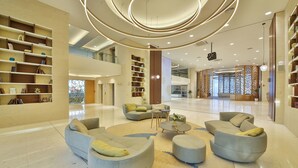 A spacious lobby with a modern design, featuring a central seating area with sofas and ottomans, surrounded by bookshelves and a decorative partition. - MARITIM Paradise Blue Hotel & Spa (Albena)